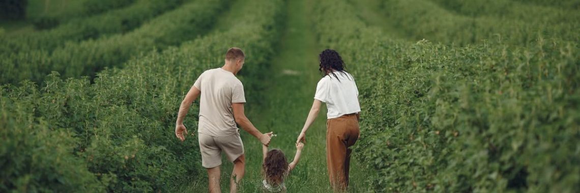 Happy family walking together through a lush green field enjoying nature and togetherness.